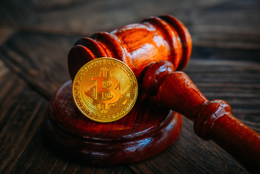Law or auction gavel and bitcoins on a wooden desk