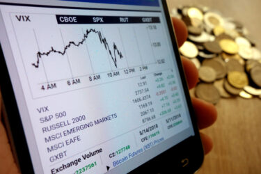 CBOE Global Markets website showing chart displayed on smartphone and stack of coins