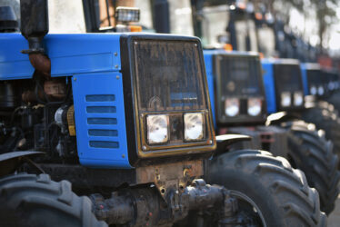 row of used identical tractors in second hand market