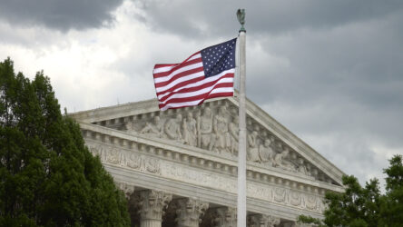 US Supreme Court, stormy sky, American Flag. Equal Justice Under Law engraving is seen over portico