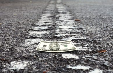 Crumpled money on a deserted road leading into the horizon for the concept of American dream.