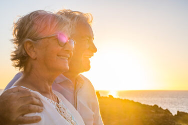 Couple of two happy seniors having fun in holiday trip together at vacations in the beach with the sea or ocean at the background