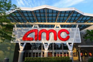 AMC movie theater front glowing in the setting sun with the name shining bright red.