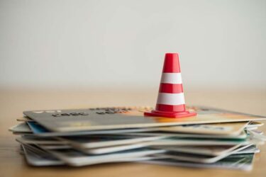 Image of a construction cone on top of a pile of credit cards