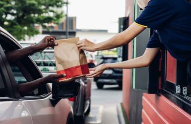 Hand Man in car receiving coffee in drive thru fast food restaurant.