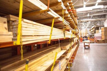 Selective focus timber shelves aisle with lumber cart, home improvement hardware store, chain link preventing warehouse rack collapse, building material framing, house, sheds construction.