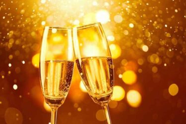 two glasses of champagne toasting against gold bokeh background