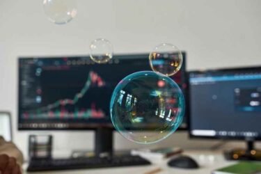 Soap bubbles with computers in the background showing stock charts.