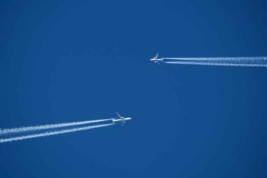 Airplane in the blue sky with contrail. Two planes in the sky.